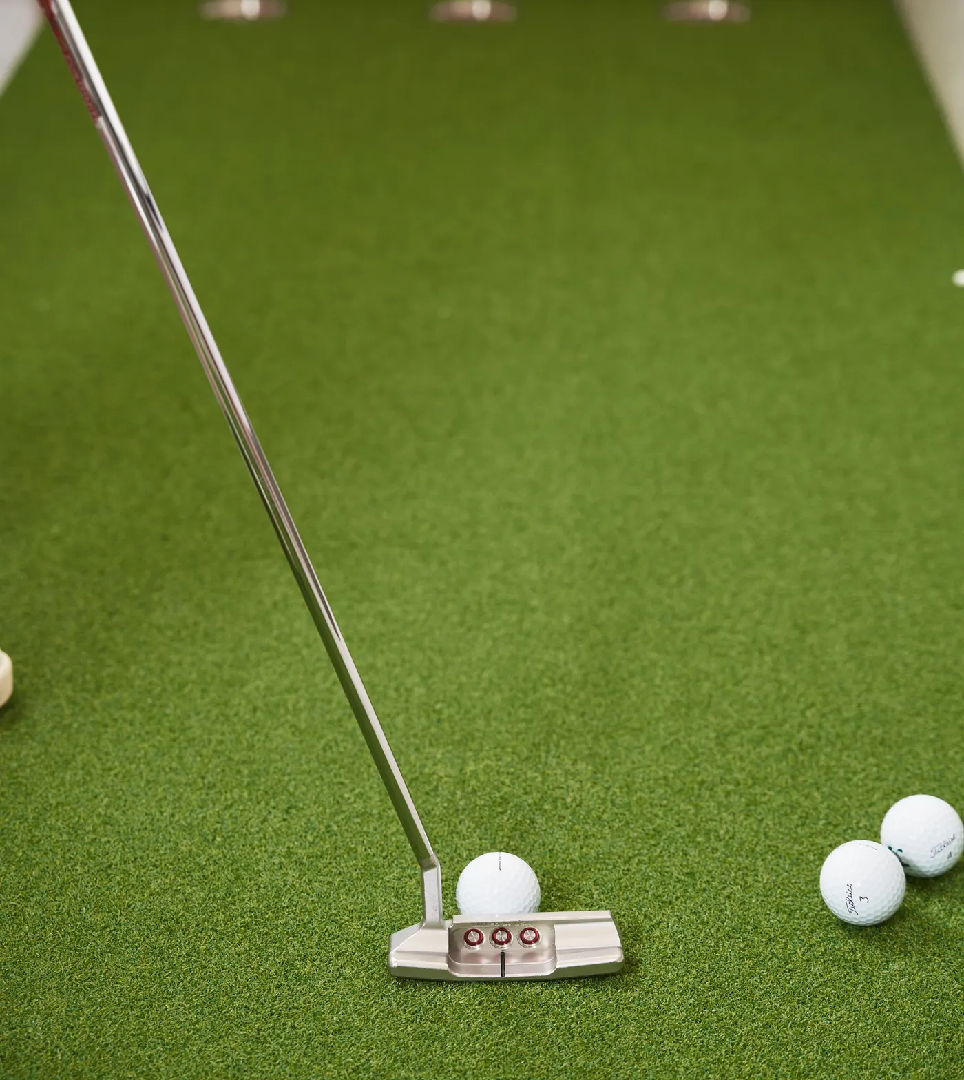 Putter lined up with a golf ball on a putting green